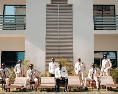 Groomsmen posing outdoors in white suits